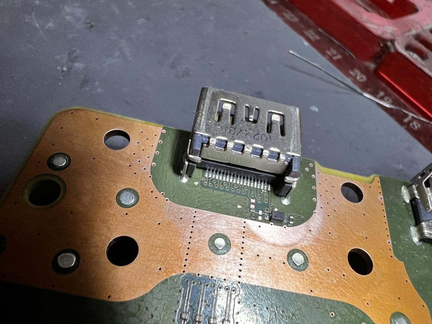 Close-up of HDMI port being micro-soldered under the microscope